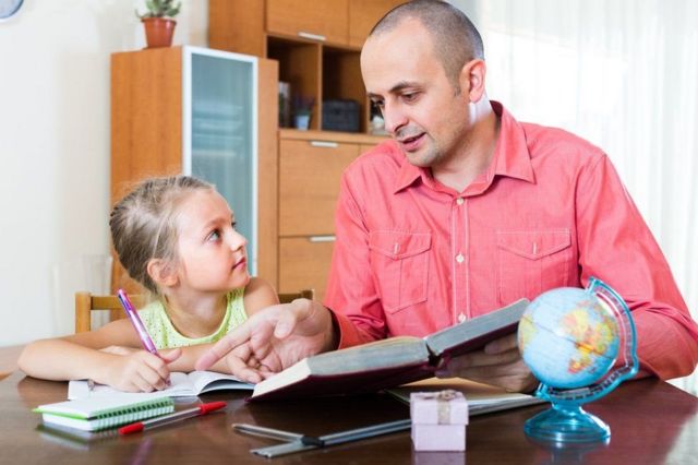 Adulto dándole clases a una niña.