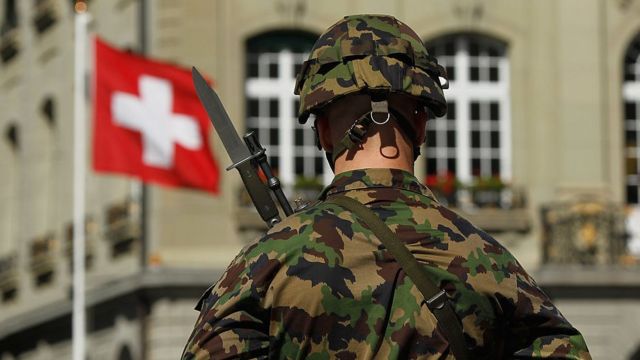 Um soldado suíço na frente de uma bandeira suíça