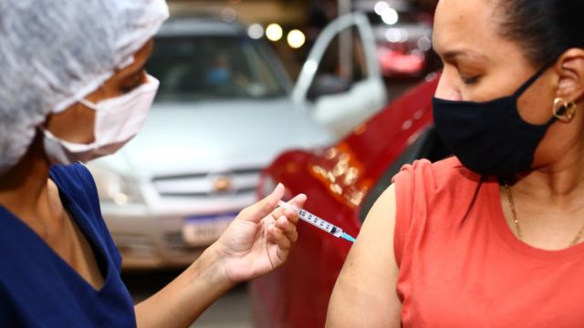 Enfermeira aplica vacina em mulher