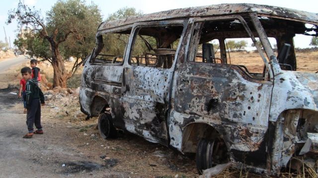 Anak-anak Suriah di dekat minibus yang terbakar akibat serangan AS di dekat desa Barisha (27/10).