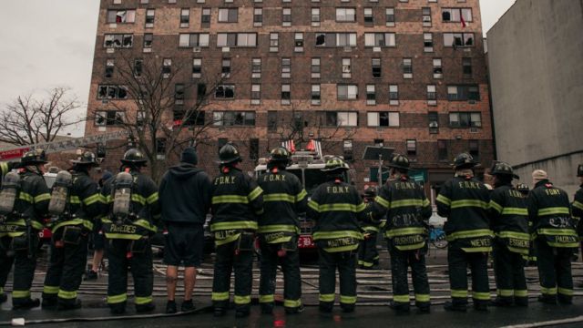 Un grupo de bomberos frente al edificio que se incendió en el Bronx, New York