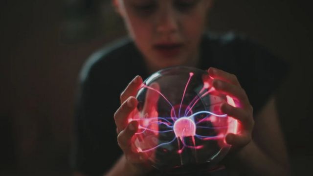 Criança segurando um globo de plasma