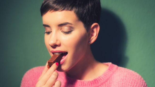 A woman bites a chocolate bar
