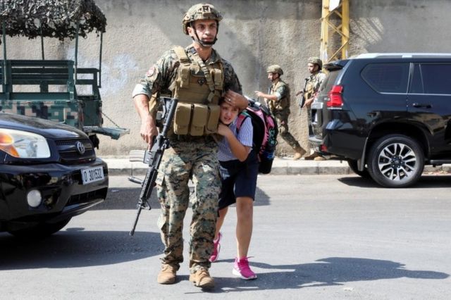 جندي لبناني يساعد تلميذة للنجاة من الاشتباكات في وسط بيروت في 14 أكتوبر / تشرين الأول 2021