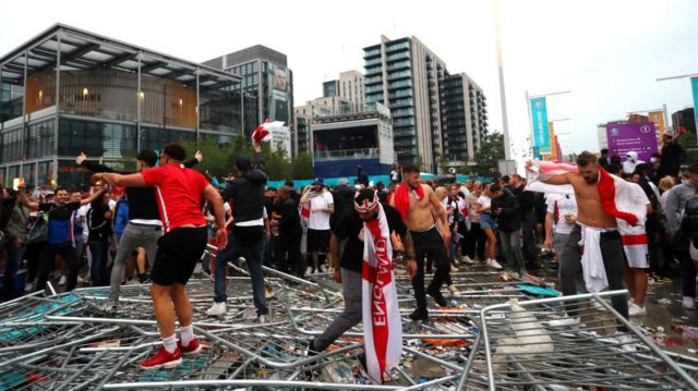 Aficionados de Inglaterra pisan vallas de seguridad fuera del estadio de Wembley. 