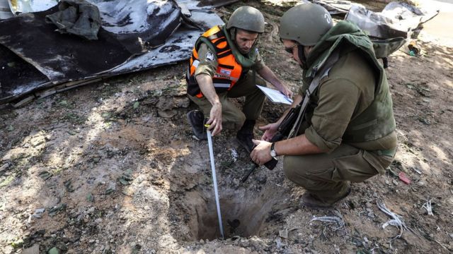 Israeli troops examine the impact of a rocket launched from Gaza (18 May)