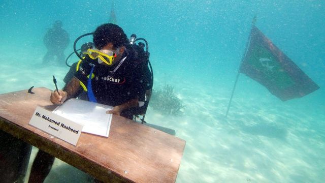 Maldives President Mohamed Nasheed, seen signing a paper while wearing diving gear.