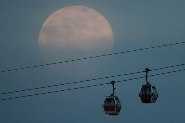 The supermoon rises in the sky above the Emirates Air Line cable car in London