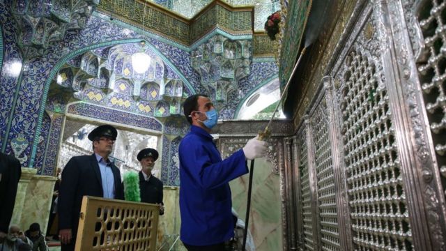 Petugas kebersihan Iran menyemprotkan disinfektan pada kuil Masumeh di kota Qom.