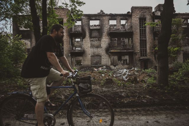Un ciudadano monta en bicicleta frente a un edificio vacío dañado mientras se producen intensos enfrentamientos en Chasiv Yar, en la provincia ucraniana de Donetsk, el 28 de junio de 2023. 