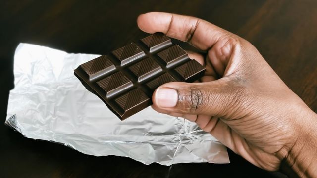 Una mano sostiene una barra de chocolate negro