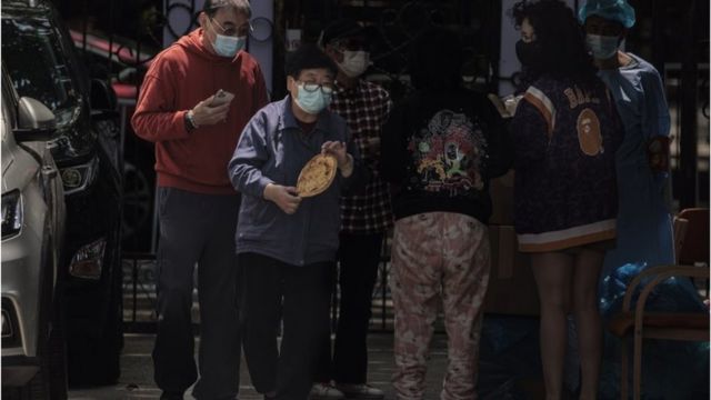 人们在中国上海的一个被封锁的住宅社区里领取面包等口粮。