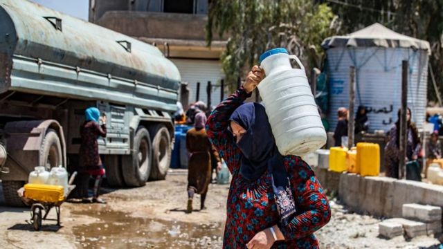 سيدة سورية تحمل حاوية مياه قدمتها منظمة اليونيسف في مدينة الحسكة شمال شرق سوريا، في 8 يوليو/تموز 2021