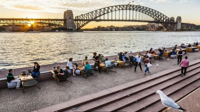 أستراليون يجلسون لتناول مشروباتهم بالقرب من النهر