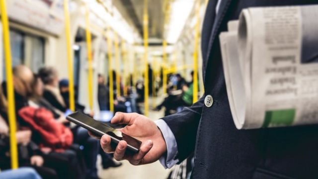Una persona usando el celular en el transporte público.