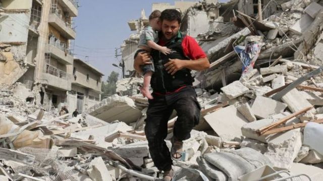 Hombre cargando un niño en Alepo