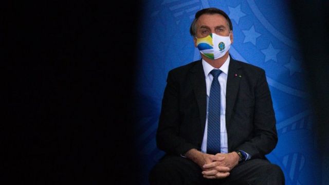 Jair Bolsonaro sentado usando máscara