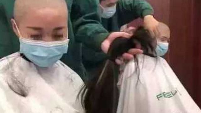 Screenshot of female medical workers getting their heads shaved