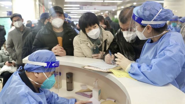 北京朝陽醫院本部急診大廳候診區患者與家屬圍著醫護人員查詢情況（中新社圖片27/12/2022）