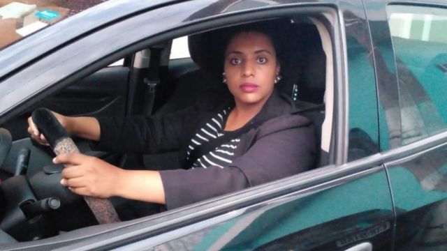 Ana Paula Aparecida de Oliveira segurando no volante do carro que usa para trabalhar como motorista de aplicativo