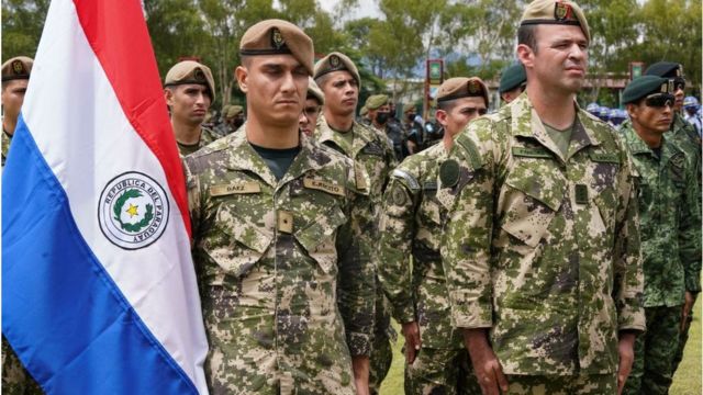 Soldados del ejército paraguayo junto a la bandera del país.