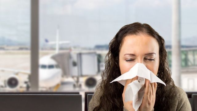 Mulher tossindo em um aeroporto