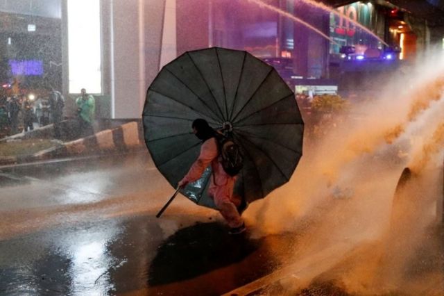 A man takes cover behind an umbrella during an anti-government protest, in Bangkok, Thailand October 16, 2020