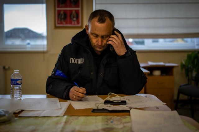 Vitaliy Lobas, the head of Buchansky District 1 police department, takes a call in his command post in a school classroom.