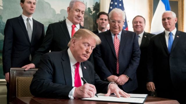 Trump firmando documento con Netanyahu.