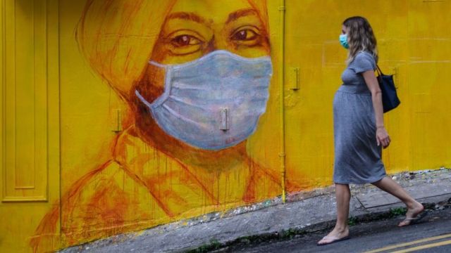 香港街頭戴口罩的路人與壁畫相呼應