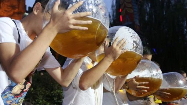 Jovens bebendo cerveja em grandes recipientes