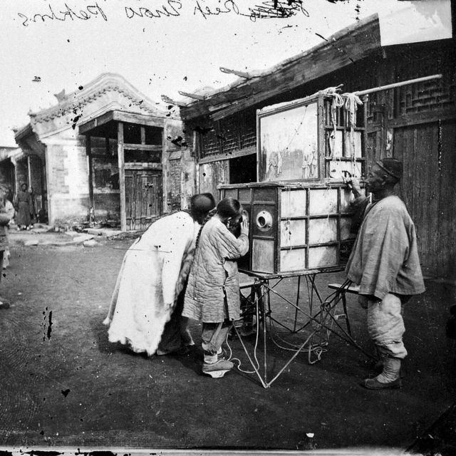 拉洋片艺人，使用的道具为四周安装有镜头的木箱（北京，1871-72年）。(photo:BBC)