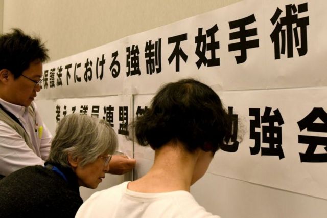 Japoneses olham escritos colados na parede