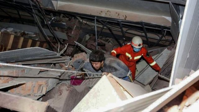A man (L) is helped by rescuers as he is pulled from the rubble of a collapsed hotel in Quanzhou, in China"s eastern Fujian province on March 7, 2020.