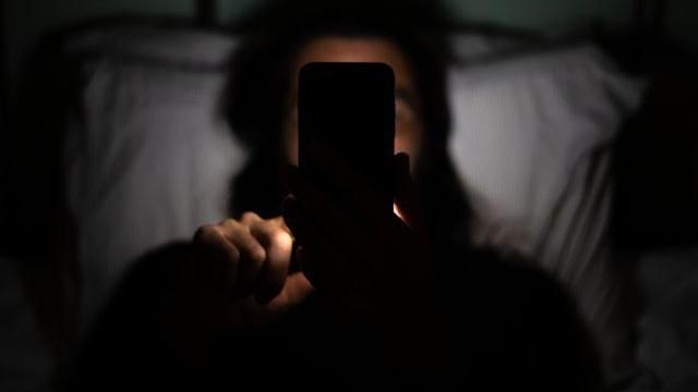 Homem vendo celular na cama