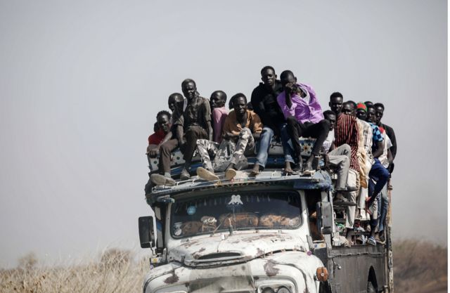 Refugiados em fuga da guerra no Sudão na garupa de um caminhão