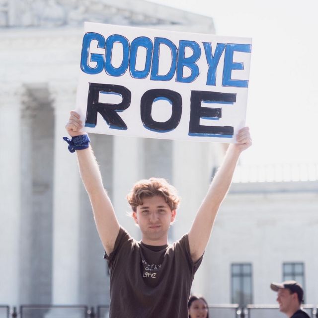 نوح سلايتر يحمل لافتة كتب عليها "وداعا رو"