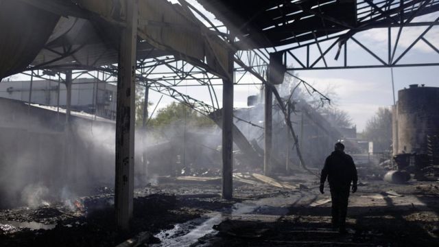 在哈尔科夫，一名男子周六穿过一座遭俄军空袭损坏并着火的工业建筑(photo:BBC)