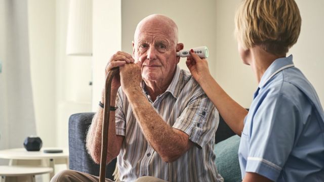 A nurse takes the temperature of an elderly man