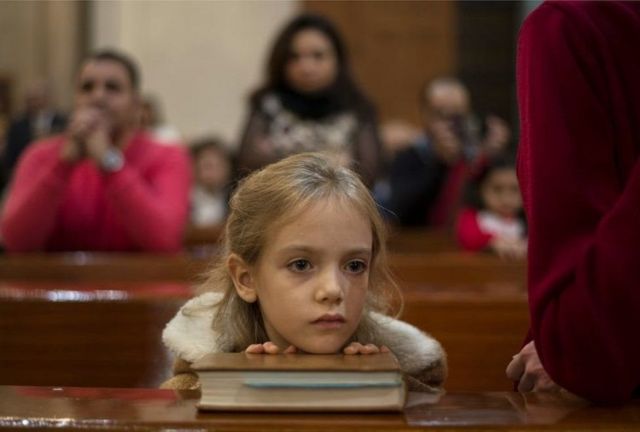 Девочка слушает рождественскую проповедь в церкви в Каире