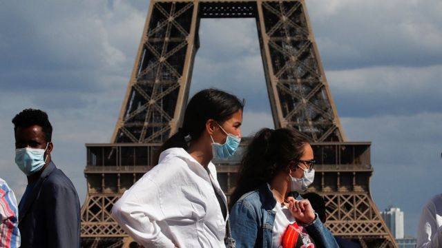 People wearing protective face masks walk at the Trocadero square near the Eiffel Tower in Paris as France reinforces mask-wearing as part of efforts to curb a resurgence of the coronavirus disease (COVID-19) across the country