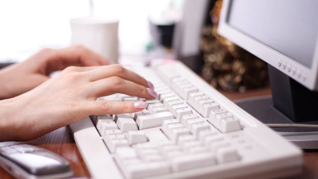 Mãos femininas digitando num teclado