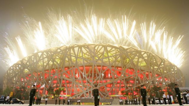 Fireworks light up the sky as paramilitary policemen stand guard outside the National Stadium during the Opening Ceremony for the Beijing 2008 Olympic Games