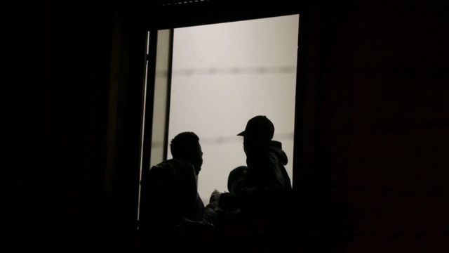 صورة لاثنين من المهاجرين يقفان على باب شقة