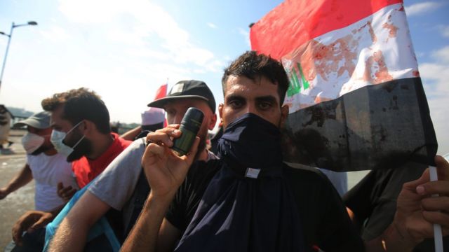 متظاهر عراقي يحمل عبوة غاز استخدمتها قوات الأمن لتفريق المتظاهرين