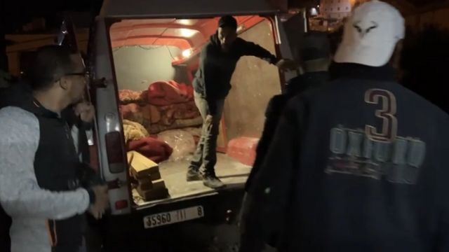 Men talking while standing behind a car at night