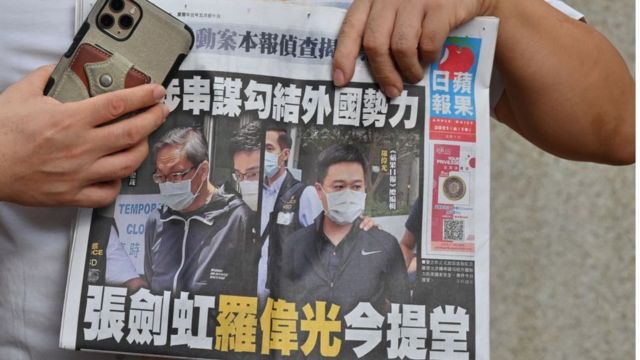 A supporter of two executives from Hong Kong's pro-democracy Apple Daily newspaper, chief editor Ryan Law and CEO Cheung Kim-hung, holds up a copy of the newspaper during a protest outside court in Hong Kong on June 19, 2021.
