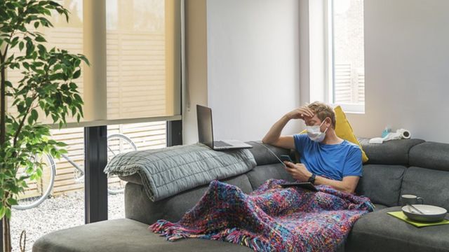 Homem sentado no sofá de máscara