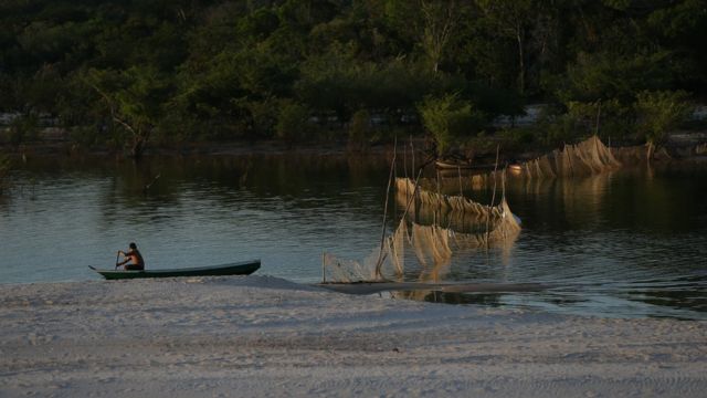 Homem rema em canoa no rio