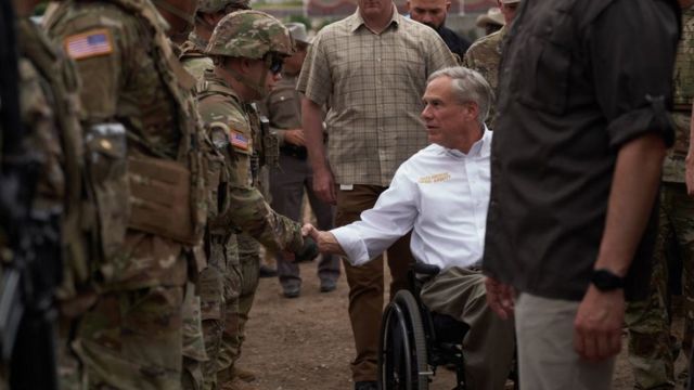 El gobernador de Texas, Greg Abbott, saludando a guardias armados en la frontera con México